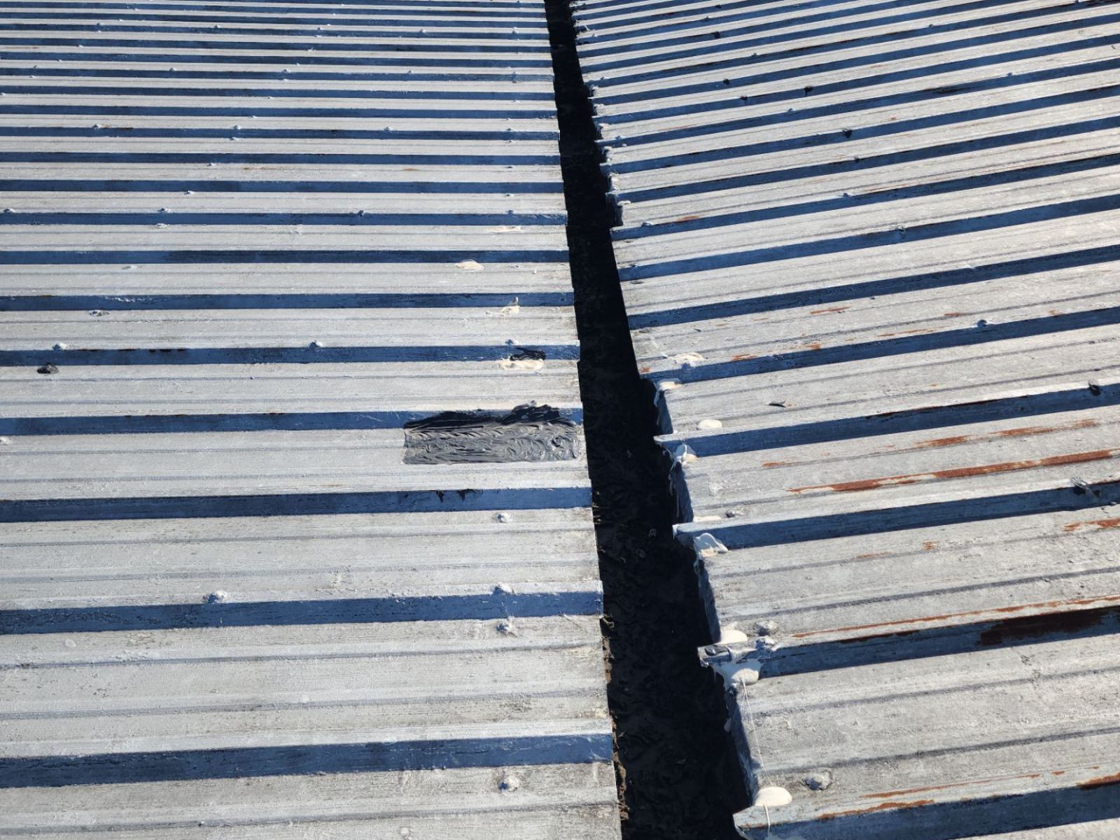 Before: weathered metal roof with rust and an open valley